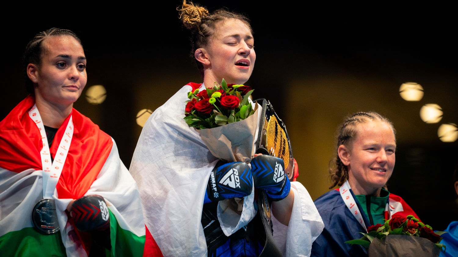 Katrina Fisher on the IMMAF podium with her medal and flowers
